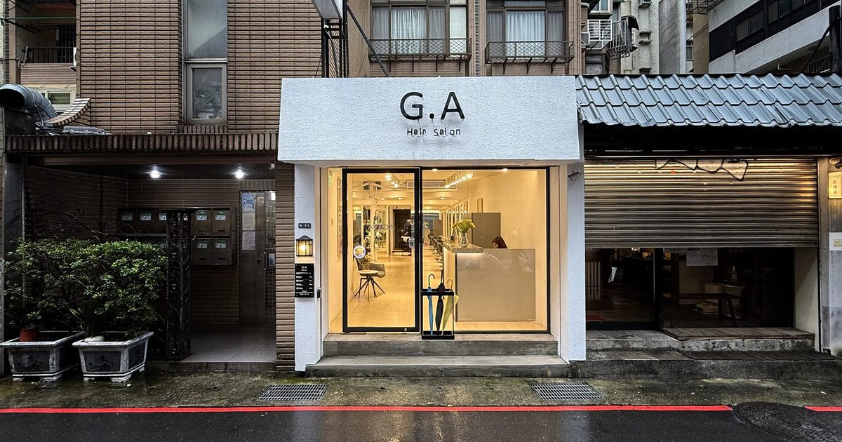 G.A Hair Salon 忠孝東路 216 巷店面外觀，雨後夜色中的白色招牌與明亮落地窗